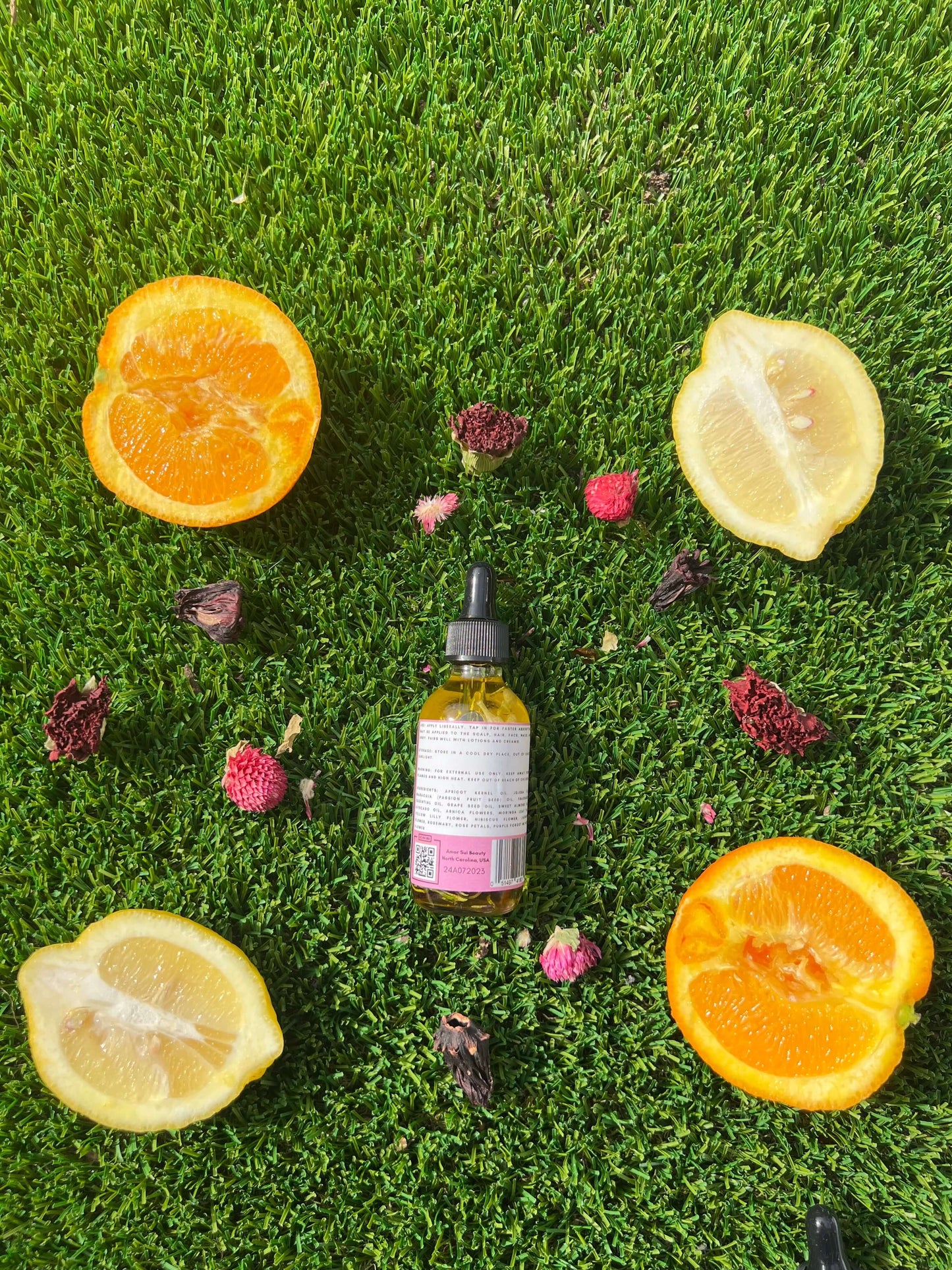 Amor Sui Multi-Purpose Botanical Oil surrounded by fresh citrus slices on green grass, highlighting natural skincare benefits.