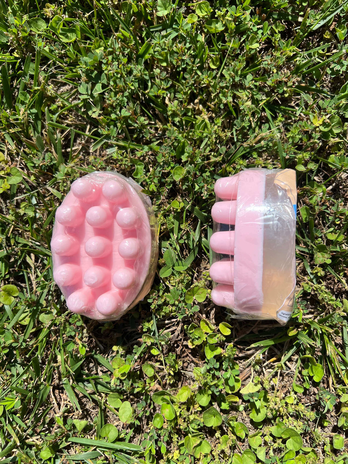 Two pink Dead Sea salt massage bars placed on grass, showcasing their textured design and luxurious appeal.